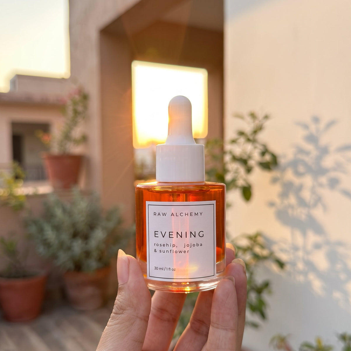 Raw Alchemy Evening face oil glowing against the sunset